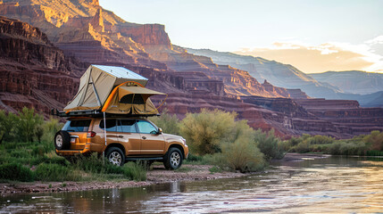 An SUV with a tent on the roof stands on the river bank against the backdrop of a mountainous landscape, embodying the spirit of travel. Offroad travel - obrazy, fototapety, plakaty