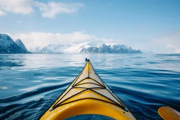 Foto auf Acrylglas A yellow kayak glides through the tranquil arctic sea, with majestic snow-capped mountains as a backdrop. © Philipp