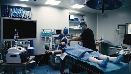 In the operating room, the surgical team prepares the patient for surgery. High tech medical...