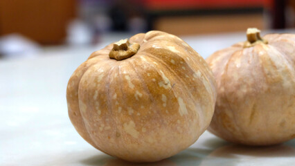 Two small pumpkins on table top. With blurred background.