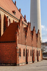 Berlin, Germany, March 6, 2024: brick facade of the Marienkirche on Alexanderplatz with the massive concrete structure of the television tower in the background