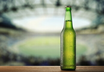 Cold Beer Bottle on Wooden Surface with Stadium Background