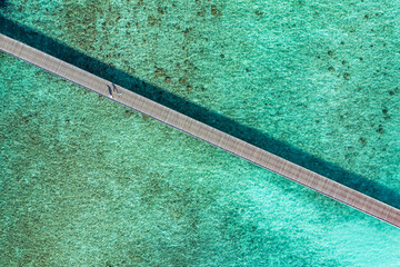 Birds eye view of wooden jetty leading out over pristine crystal clear ocean lagoon water view from drone. Aerial artistic travel background. Summer vacation seascape top view, Mediterranean coastline