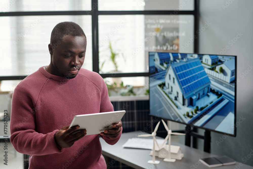 Poster african american male employee in casualwear networking or scrolling through project points against 