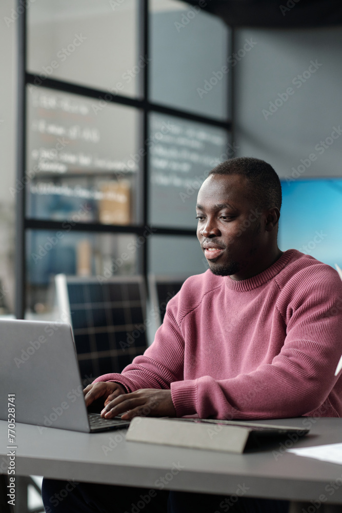 Poster african american male office worker in casualwear typing on laptop keyboard and looking at screen wh