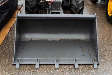 Rectangular metal bucket beside tractor on wooden floor