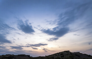 Breathtaking mountain sunset paints the sky in fiery orange hues, casting long shadows across the rugged landscape