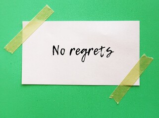 On green background stick note with handwritten text NO REGRETS - to live a life without feeling bad about what you did in the past,  to a decision without feeling sorrow or remorse for 