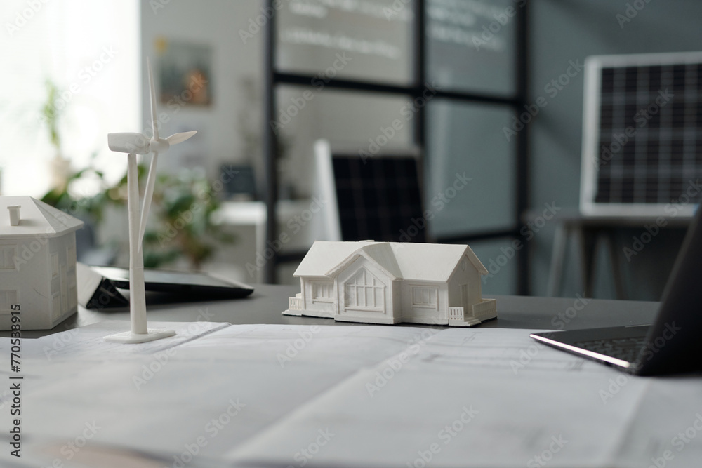 Poster workplace of modern architect with unrolled blueprint surrounded by laptop, models of houses and win