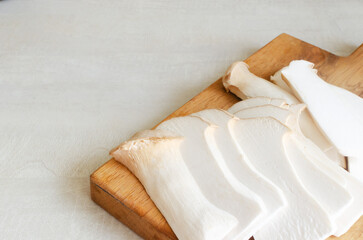 Eryngii mushroom on a wooden cutting board on a white table. The process of cooking Gochujang King...