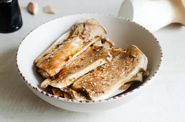 Eryngii mushroom in a white bowl with a marinade of soy sauce, garlic and chili paste. The process...