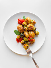 Roasted new potatoes and Brussels sprouts with cherry tomatoes and basil on white plate, healthy eating concept for weight loss.