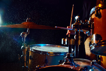 Close-up of drum set on black background with flashlights. Male musician playing drums. Live performance. Concept of music, instruments, concert, sound, equipment, festival