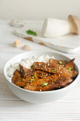 Eryngii mushroom fried with sesame and green onion and white boiled rice in a gray bowl. Dishes Gochujang King Oyster Mushrooms. Traditional Korean cuisine. Vertical orientation.