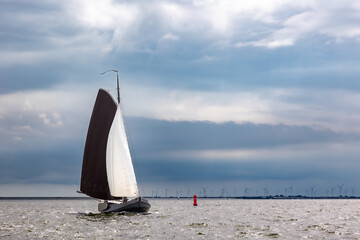 Traditional old wooden flat bottomed boats on the World Heritage Wadden Sea, the Netherlands. Calm water and brooding dark storm Dutch skies, brown sails.