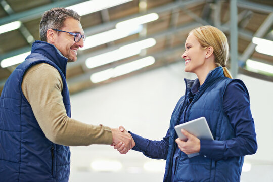 Warehouse, man and woman shaking hands, tablet and happiness for agreement or deal in storage. Business, client and supplier with smile, male person and girl together in meeting and partnership