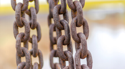 Łańcuchy grube, zardzewiałe i zwisające w splątany „warkocz”. Stare łańcuchy zwisające z wyposażenia tamy rzecznej w zimowe popołudnie.