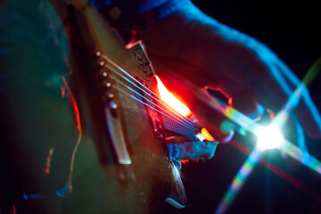 Intense close-up of bass guitar playing, with colorful stage lights. Male musician, solo performer...