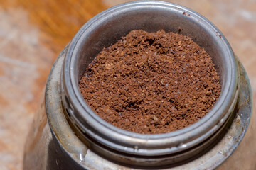 Kawa mielona umieszczona w sitku tradycyjnej włoskiej macchinetta (ekspres do kawy). Przygotowanie do procesu parzenia.Parzenie kawy w specjalnym tradycyjnym urządzeniu umieszczonym na palniku gazowym - obrazy, fototapety, plakaty