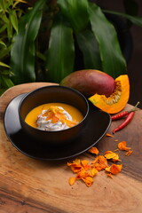 Thai spicy pumpkin, mango and coconut milk soup with kaffir lime leaves , red chilli and galangal roots powder. Vegan, healthy food, gluten-free.