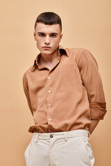 Portrait of handsome man in beige shirt with hands over his back on beige background