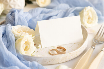 Folded Card near light blue tulle fabric and cream flowers on plate close up, copy space, wedding...