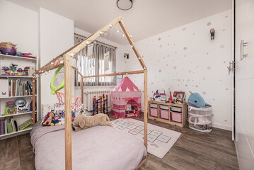 Children's bedroom with a large built-in wardrobe with white doors, shelves full of books and toys...
