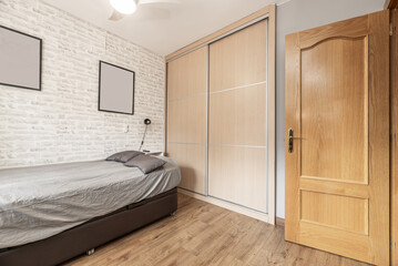 Youth bedroom with single bed with pink bedspread and large built-in wardrobes  