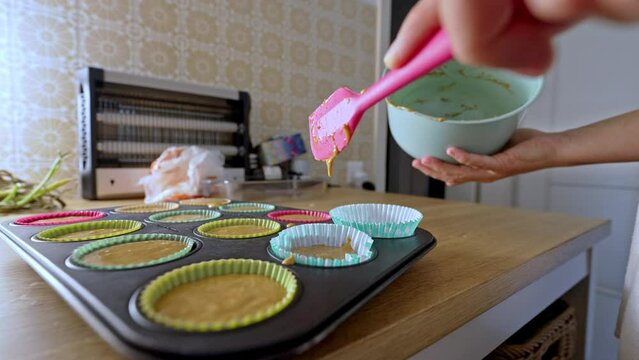 Woman&rsquo;s Hands With Silicone Spatula Pouring Remaining Cupcake Batter Into Mold