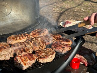 Steaks being cooked on the grill, close-up. A man cooks meat on a gas grill. Cooking outdoors, picnic.
