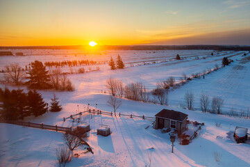 Fototapeta premium High angle view of beautiful sunrise on snowy fields seen during an early morning winter, Cacouna, Québec, Canada