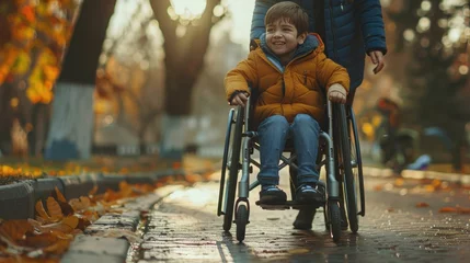 Fotobehang A beautiful little boy with a disability walks in a wheelchair with his mom at sunset. A child with disabilities © masyastadnikova