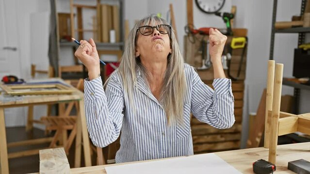 Furious middle-age woman, grey hair flying, furiously scribbles on paper in carpentry workshop, mad, screaming with deep-rooted anger and frustration