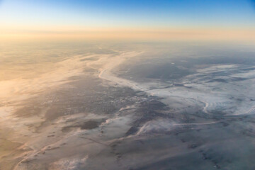 aerial high altitude image of town, earth covered in layer of fog or mist in early morning soft...