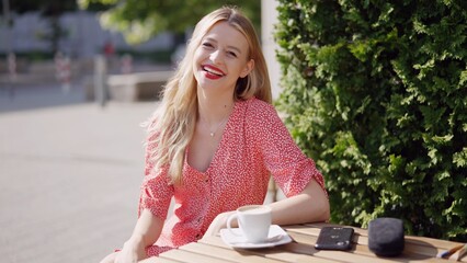 Smiling Woman Enjoying Coffee Outdoors on a Sunny Day