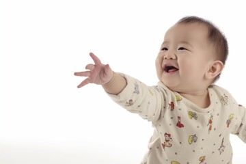 A giggling baby raises an arm in delight, wearing a white t shirt against a white backdrop