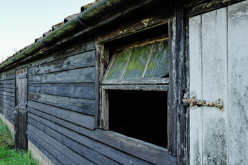 Derelict horse stable and wooden outbuildings seen on an old English dairy farm in the UK. A horse stable door can be seen in the background. - obrazy, fototapety, plakaty