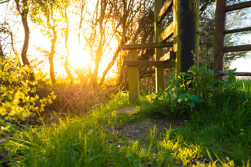 Springtime sun seen setting in a lush meadow next to a wooden steeple used as part of a public...