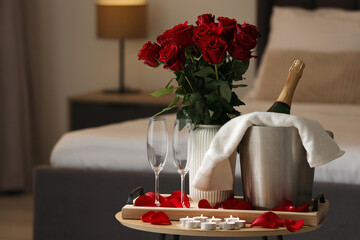 Honeymoon. Sparkling wine, glasses and bouquet of roses on wooden table in room. Space for text