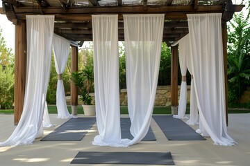 yoga session on a mat under a pergola with white curtains