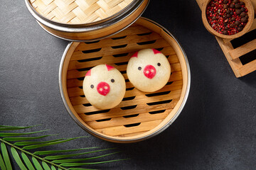Cute pig-shaped steamed Bao buns in a bamboo steamer, a playful addition to traditional Chinese dim sum, top view
