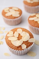 Muffins with fresh almond flakes on white table, closeup