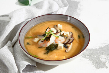 Traditional Miso Soup with Shrimp, Tofu, and Mushrooms, Garnished with Green Onions in a Stoneware...