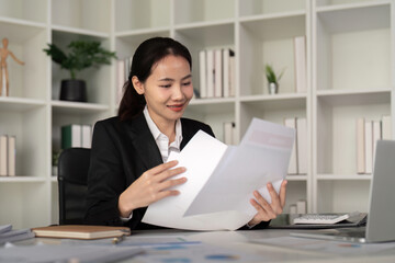 Young business woman asian or employee accounting bookkeeping documents checking financial data or marketing report working in office with laptop. Paperwork management