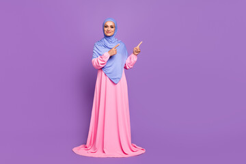 Ful length photo of cute millennial lady index ad wearing blue arabic head wrap pink dress isolated over purple color background