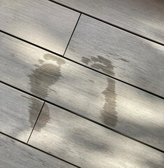 Damp footprints on wooden decking floor. - obrazy, fototapety, plakaty