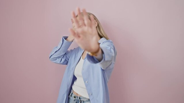 Blonde woman distressed in pink, her eyes hidden with hands, expressing fear and embarrassment through a stop gesture. an unmistakable portrayal of negative emotion.