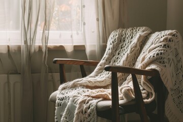 cozy nook with a knitted blanket draped over the chair - obrazy, fototapety, plakaty