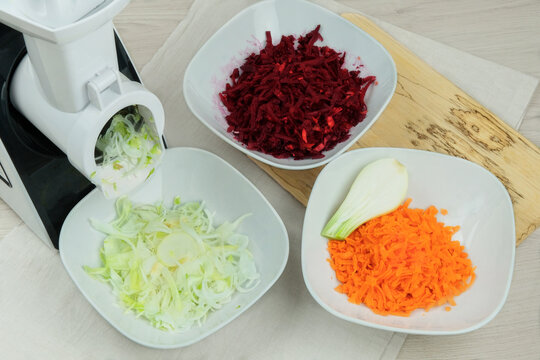 Onion, carrot and beet in a vegetable cutter on kitchen. Chopped carrot is falling into a bowl. Homemade healthy food. Health line.