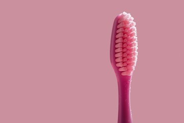 Soft pink toothbrush on a matching background, focusing on bristles, suggesting gentle dental care